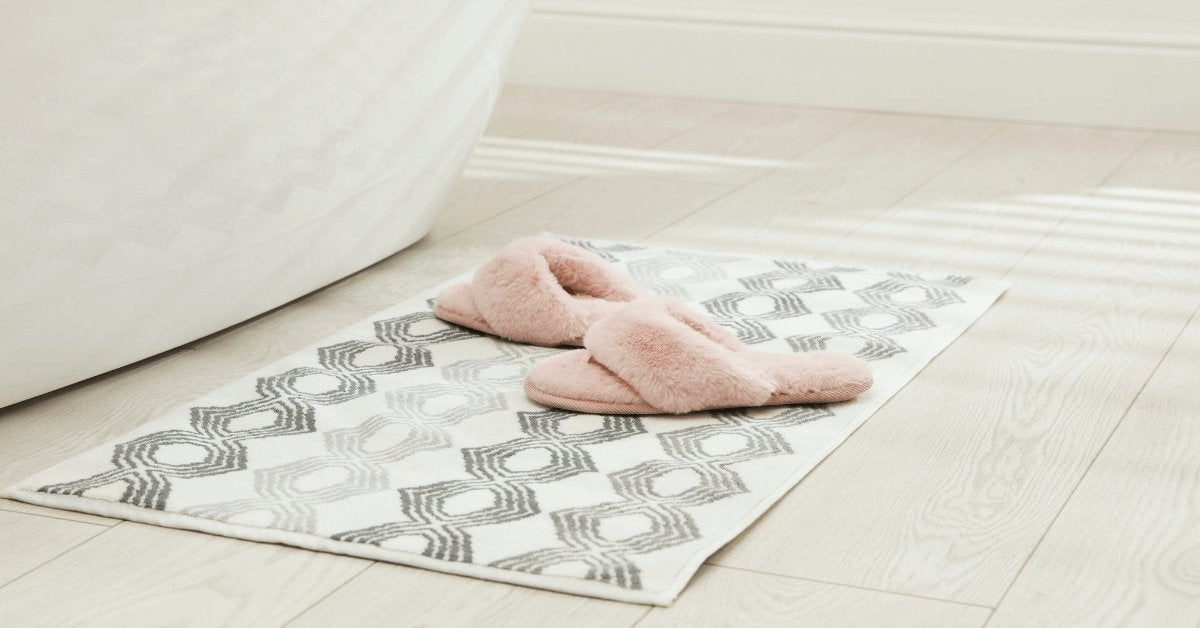 blue tufted microfibre noodle bath mat on bathroom floor at the edge of shower