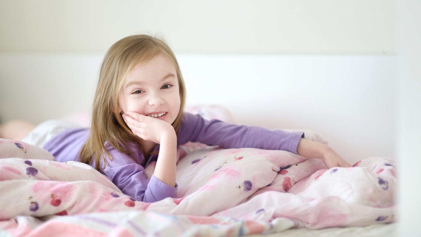 little girl on bed wearing purple pyjama top