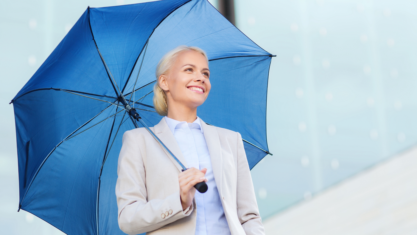 lady in white suit holding a blue umbrella in the rain
