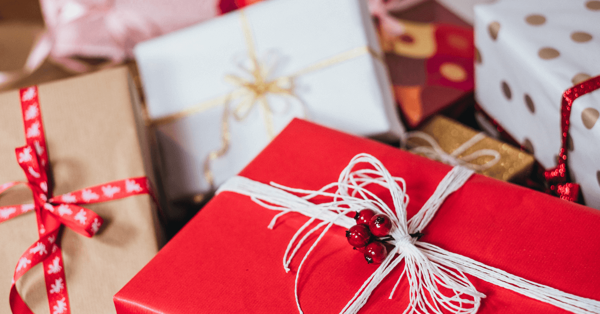 pile of red and white wrapped christmas gifts with festive ribbons and berries