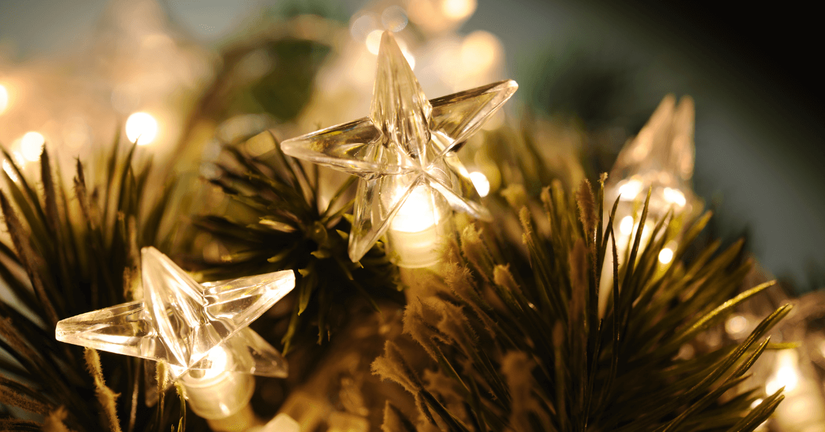warm white star shaped christmas lights on pine garland at night