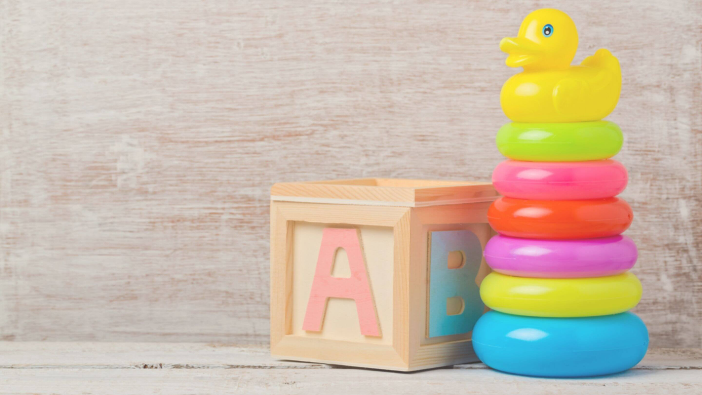 baby toys on wooden counter with a giant ABC block and a duck stacking ring playset