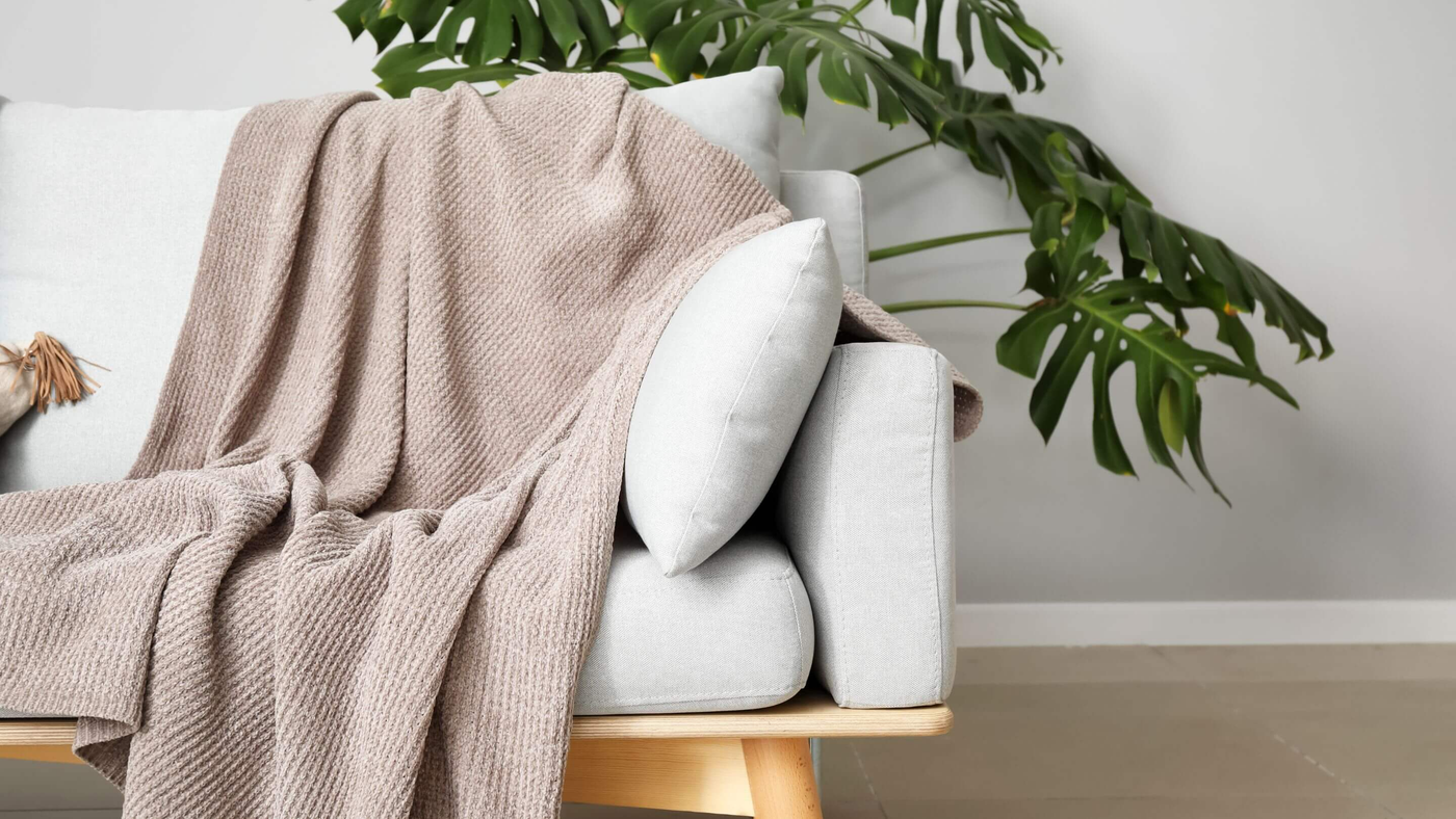 white fleecy blanket draped over taupe coloured textured sofa 