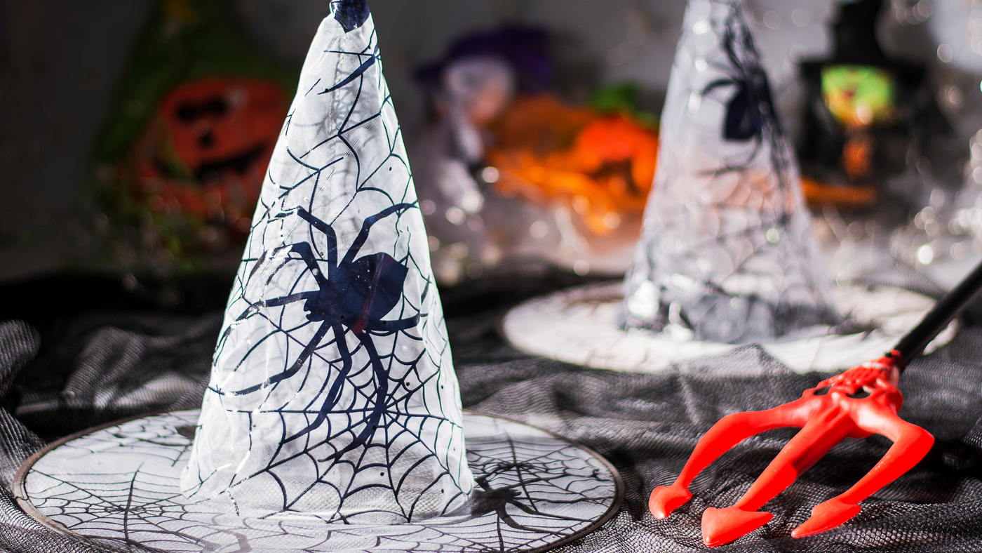 spider web witches hat on party table beside devil fork weapon