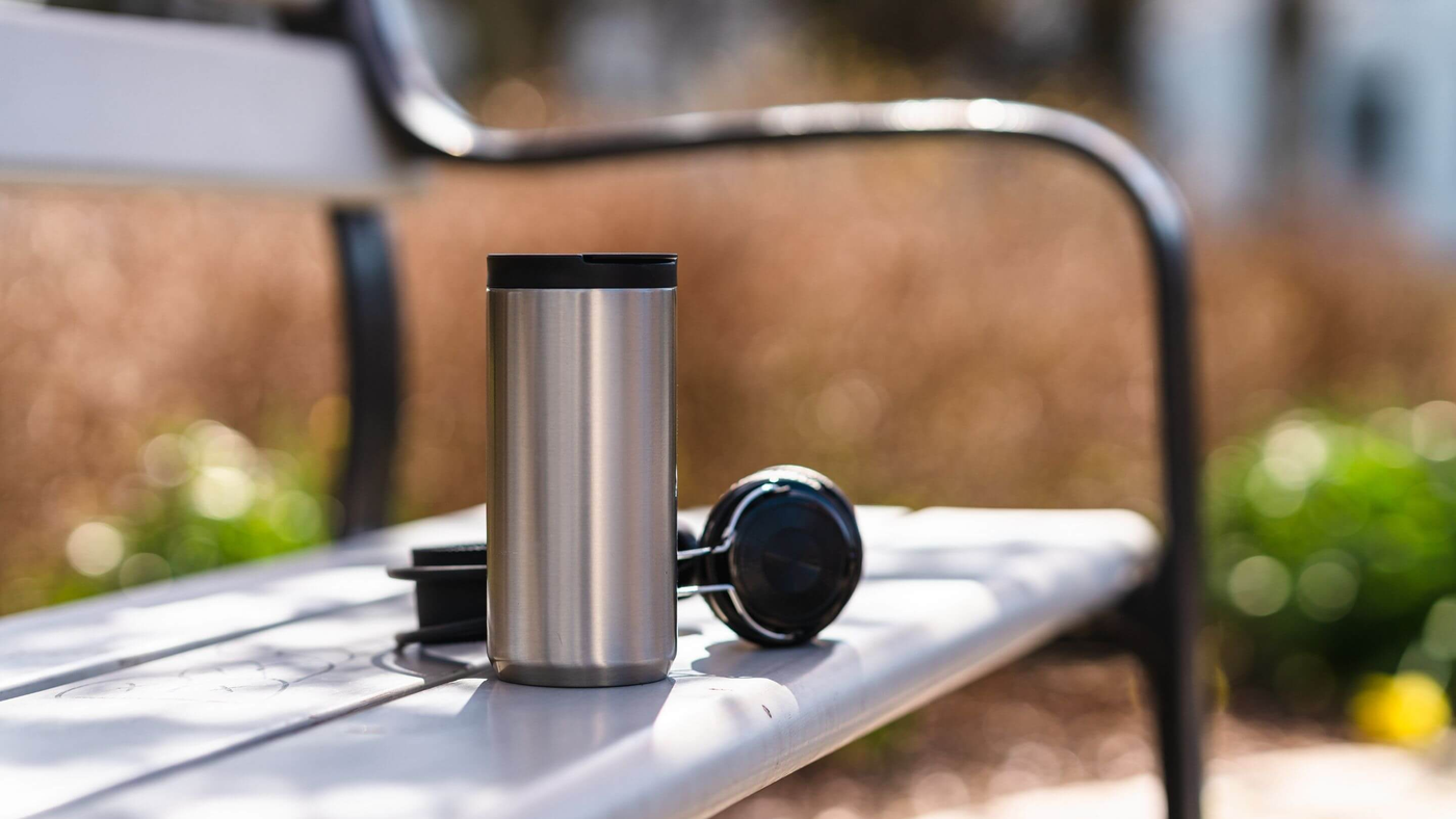 stainless steel travel mug on outdoor bench