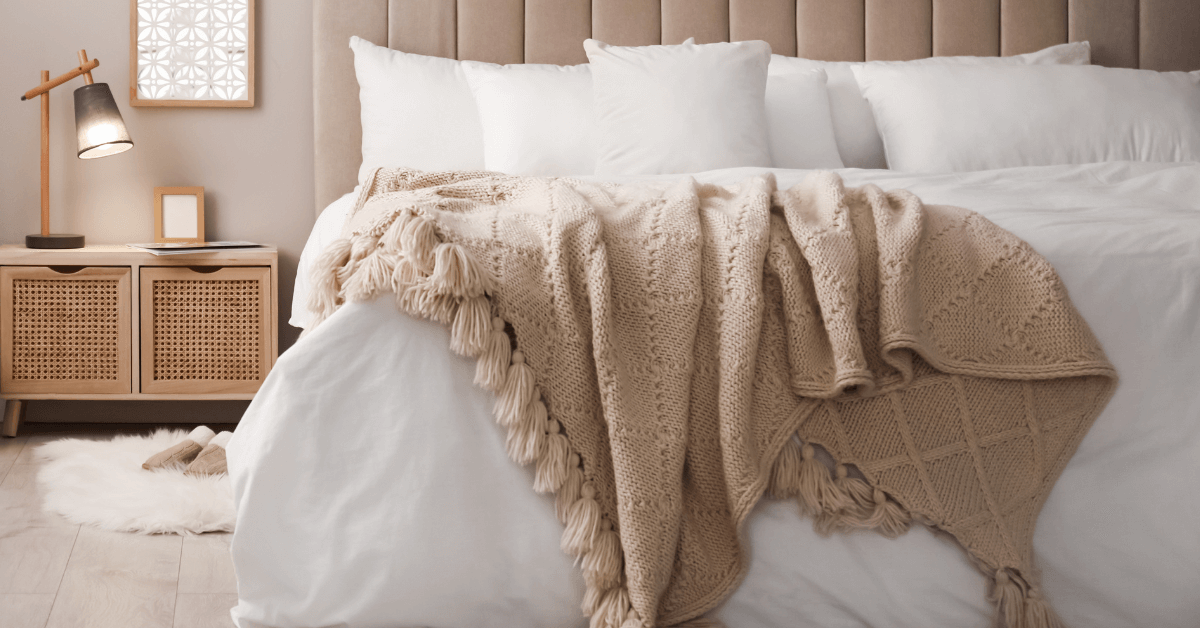 white bed featuring beige coloured blanket throw draped over the edge with contemporary rattan furniture in the background
