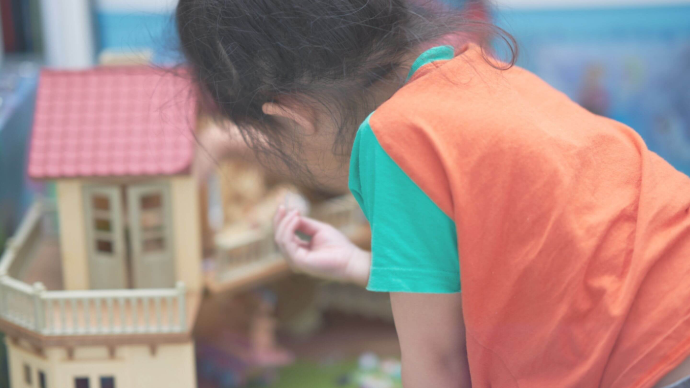 little girl playing with dolls house