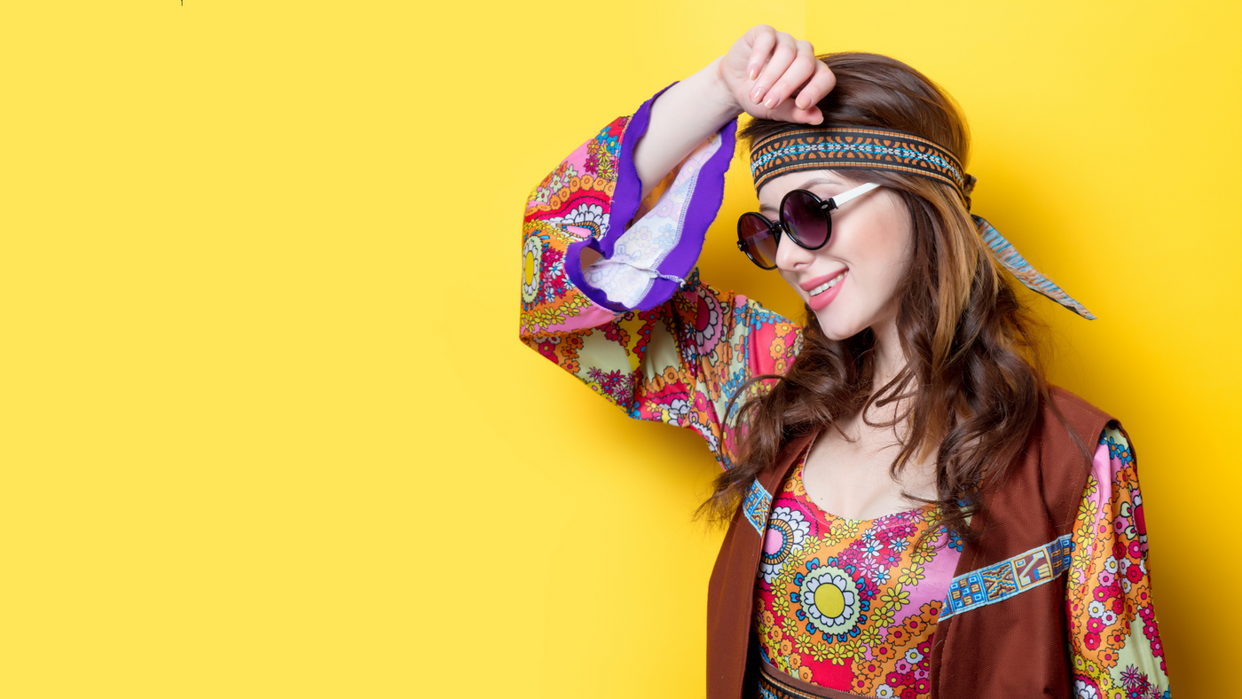 girl dressed as a retro hippie with headband and sunglasses against a yellow background