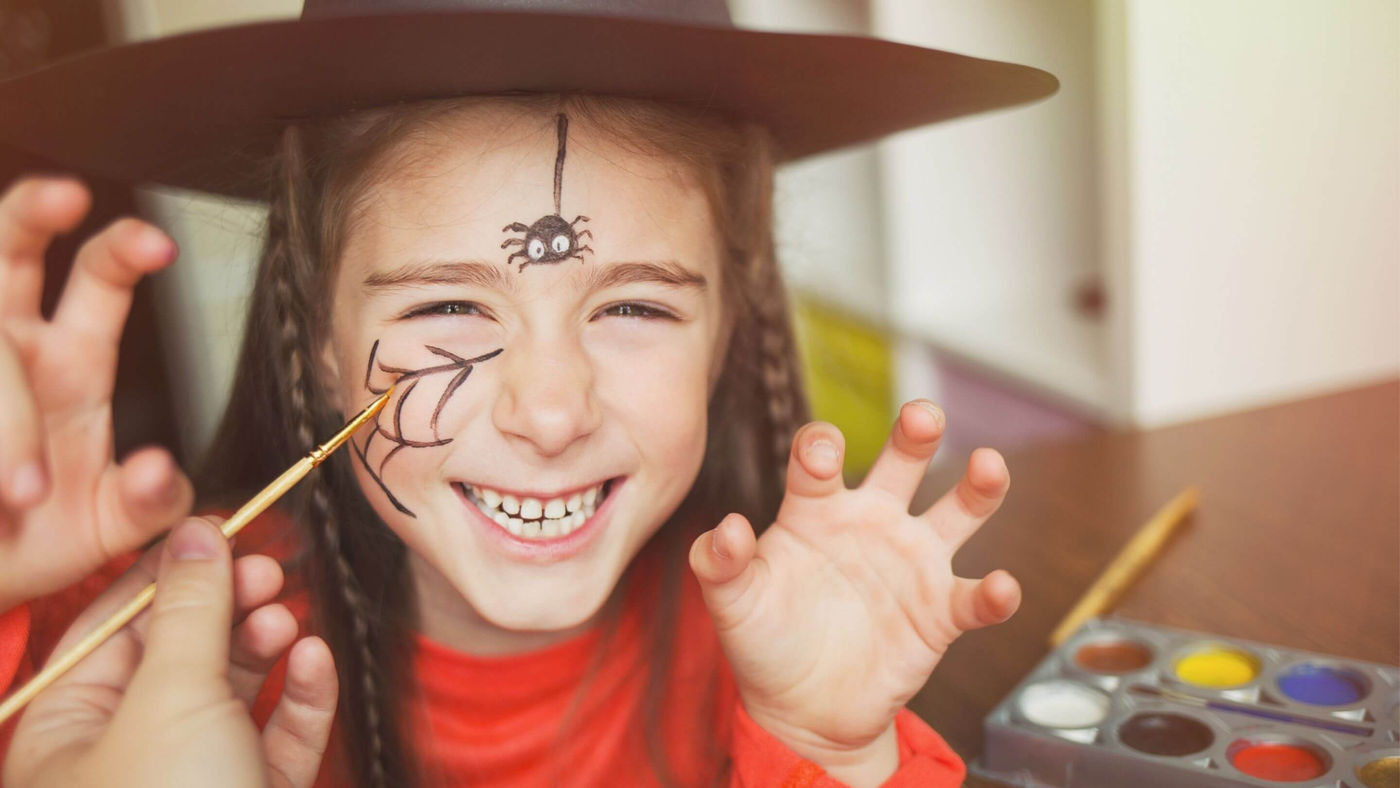 little girl getting her face painted with spider and cobweb