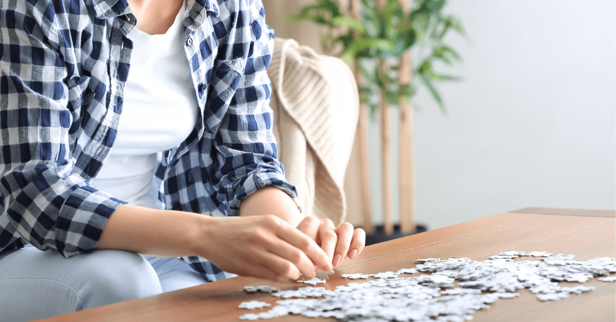 person in living room doing jigsaw puzzle on coffee table