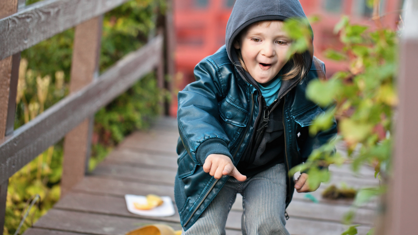 little boy wearing leather jacket playing in the garden at lunchtime