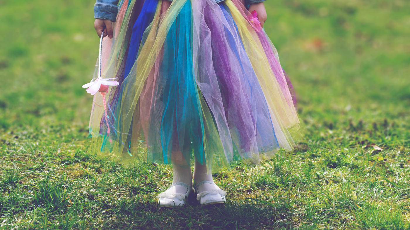 little girl wearing rainbow coloured tutu in the park