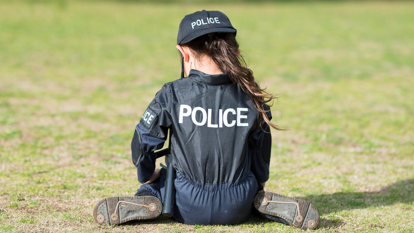 little girl dressed up in a police costume playing in the park
