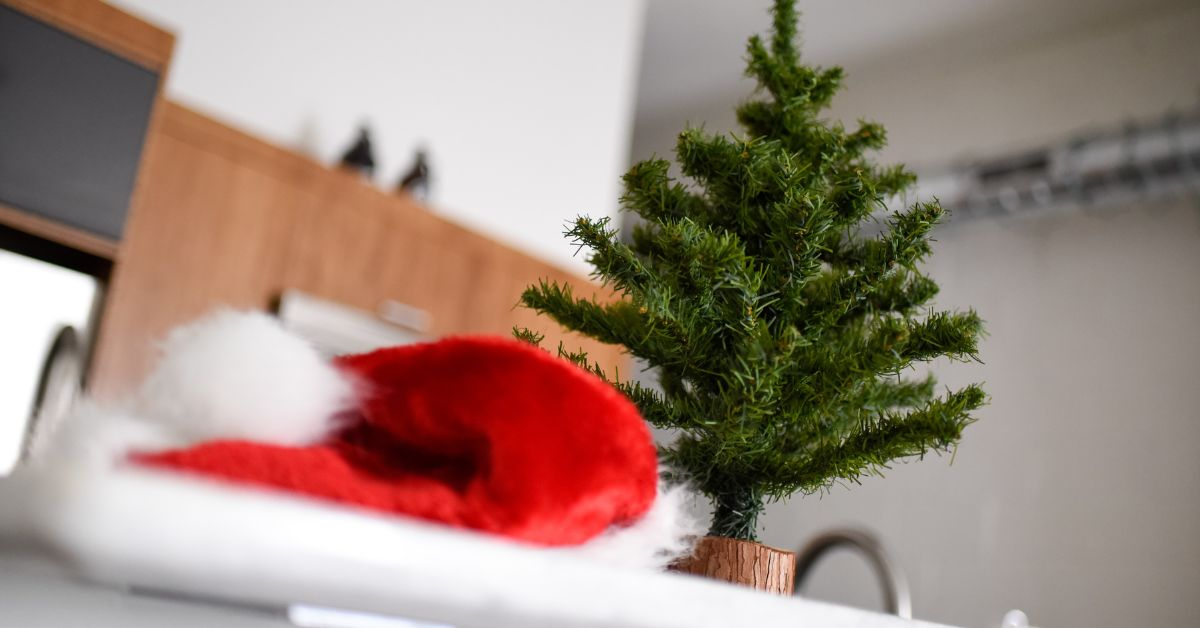 mini christmas tree on kitchen table beside santa hat