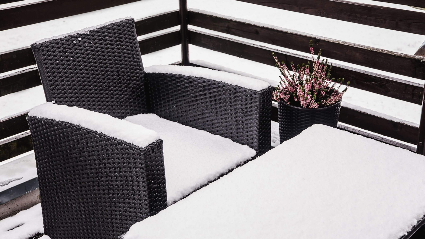 rattan garden furniture covered in a thick layer of snow