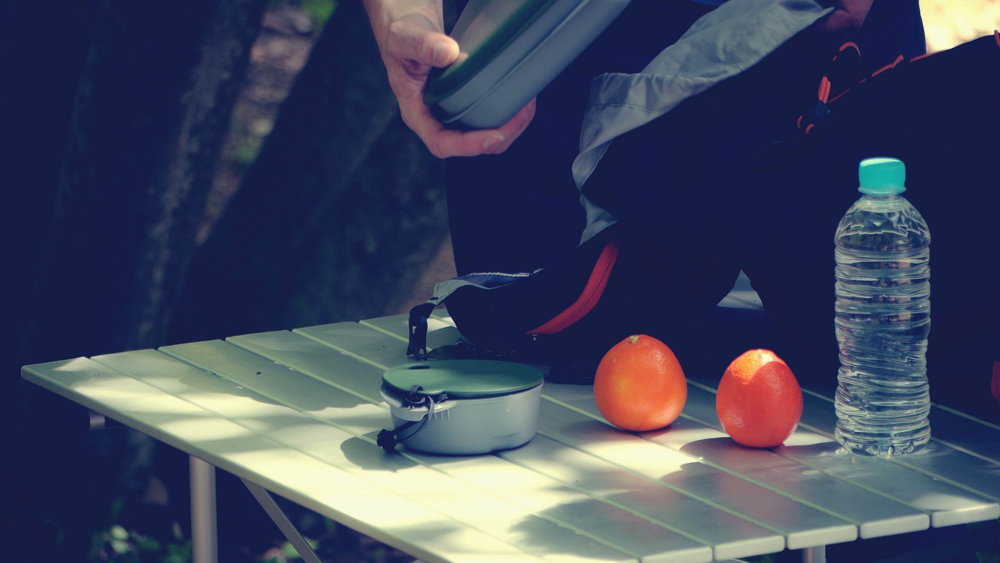 camping table with person laying out food and accessories