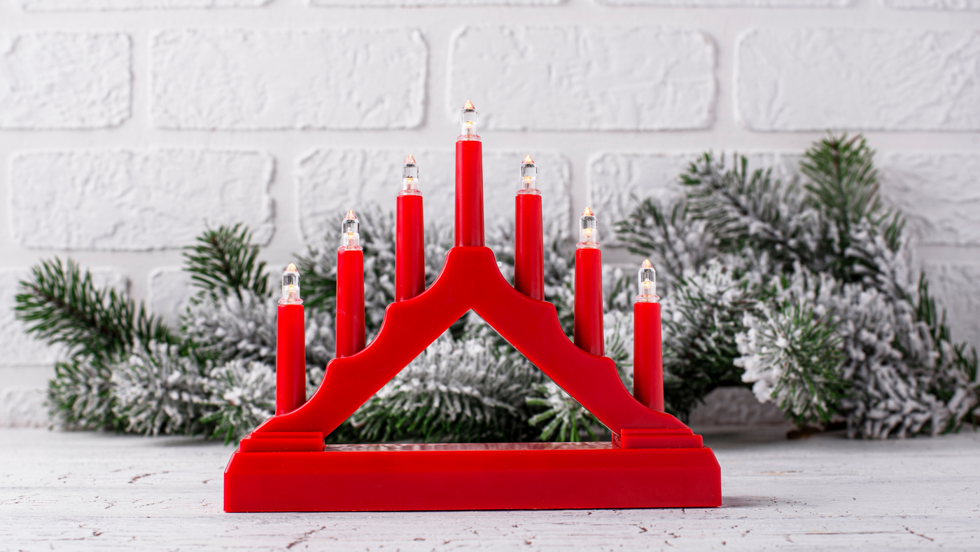 red christmas candle bridge with warm white lights in front of a snow flocked garland