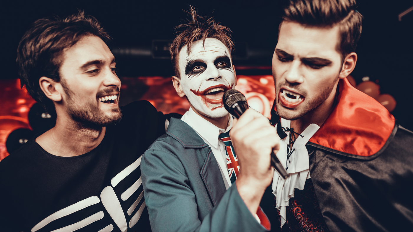 three men on halloween doing karaoke dressed as a skeleton, the joker and a vampire