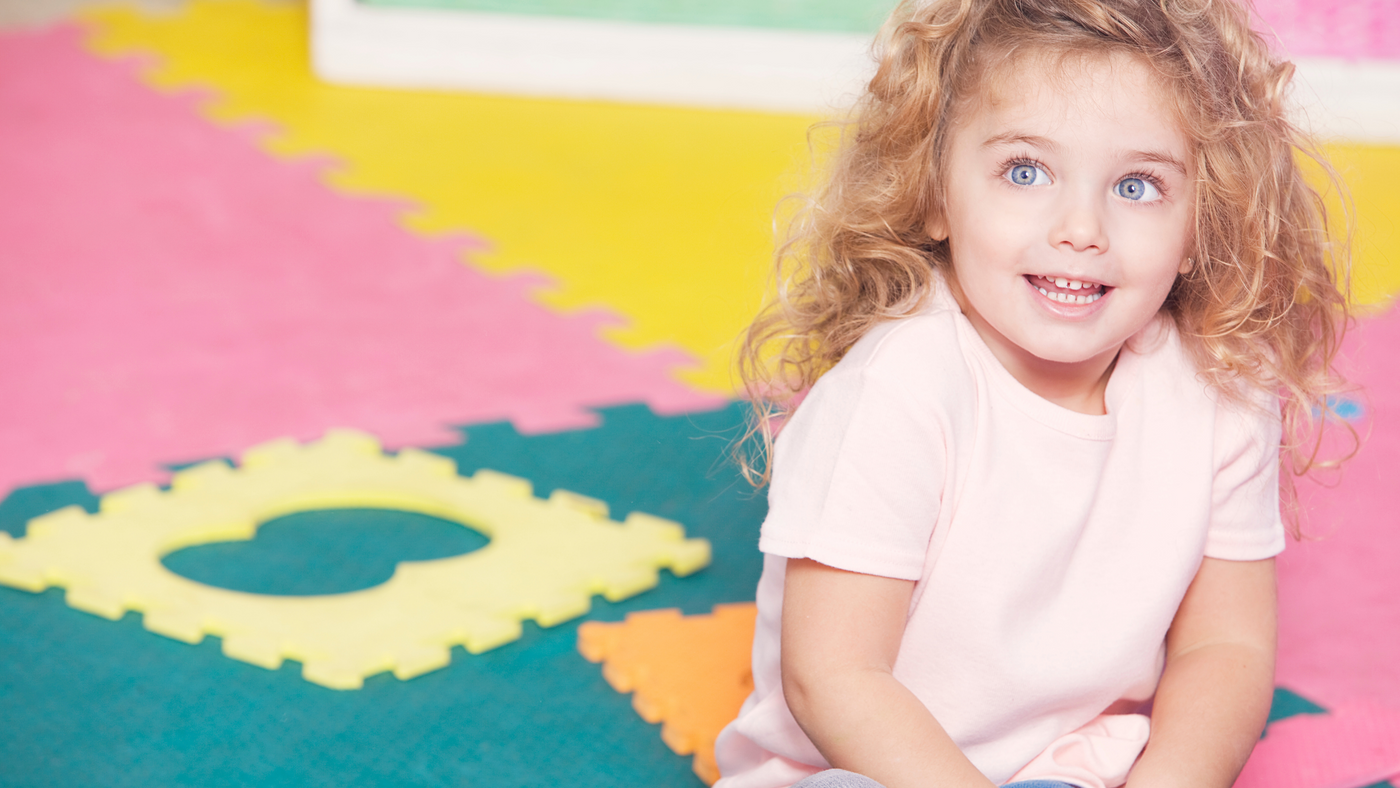 little girl on playing mat wearing pink tshirt