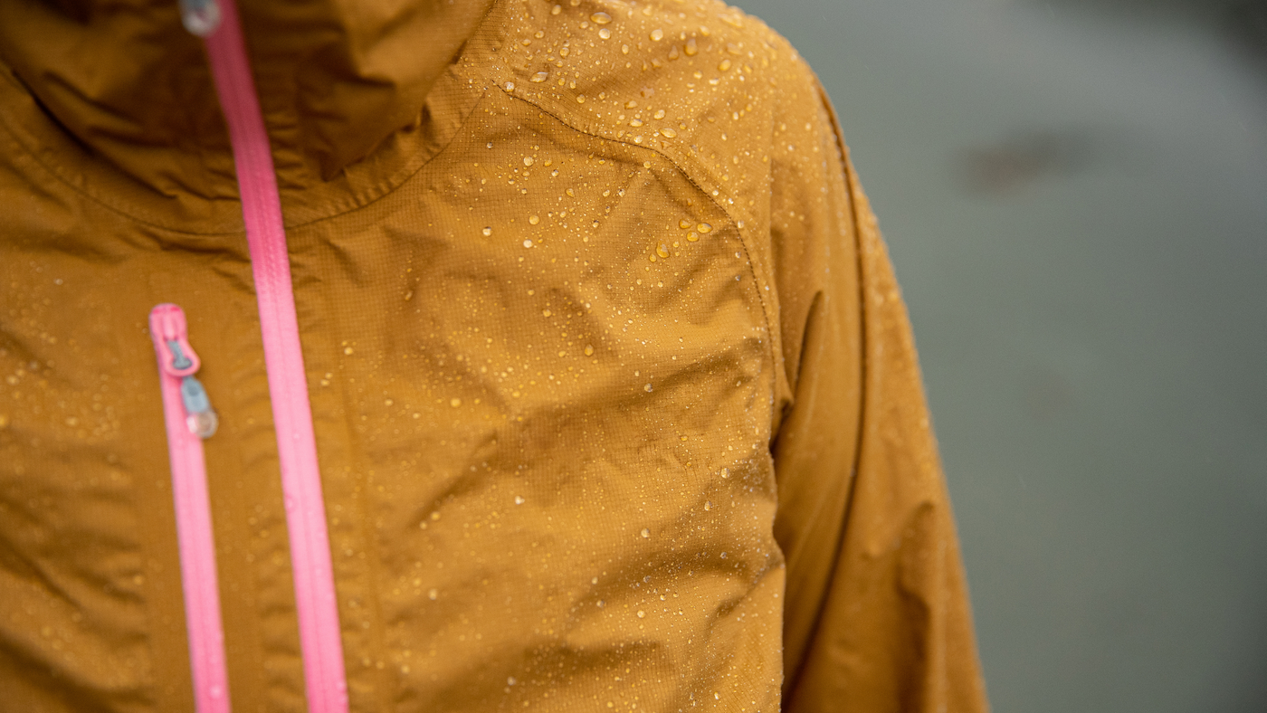 close up of person wearing yellow rain jacket with water droplets 