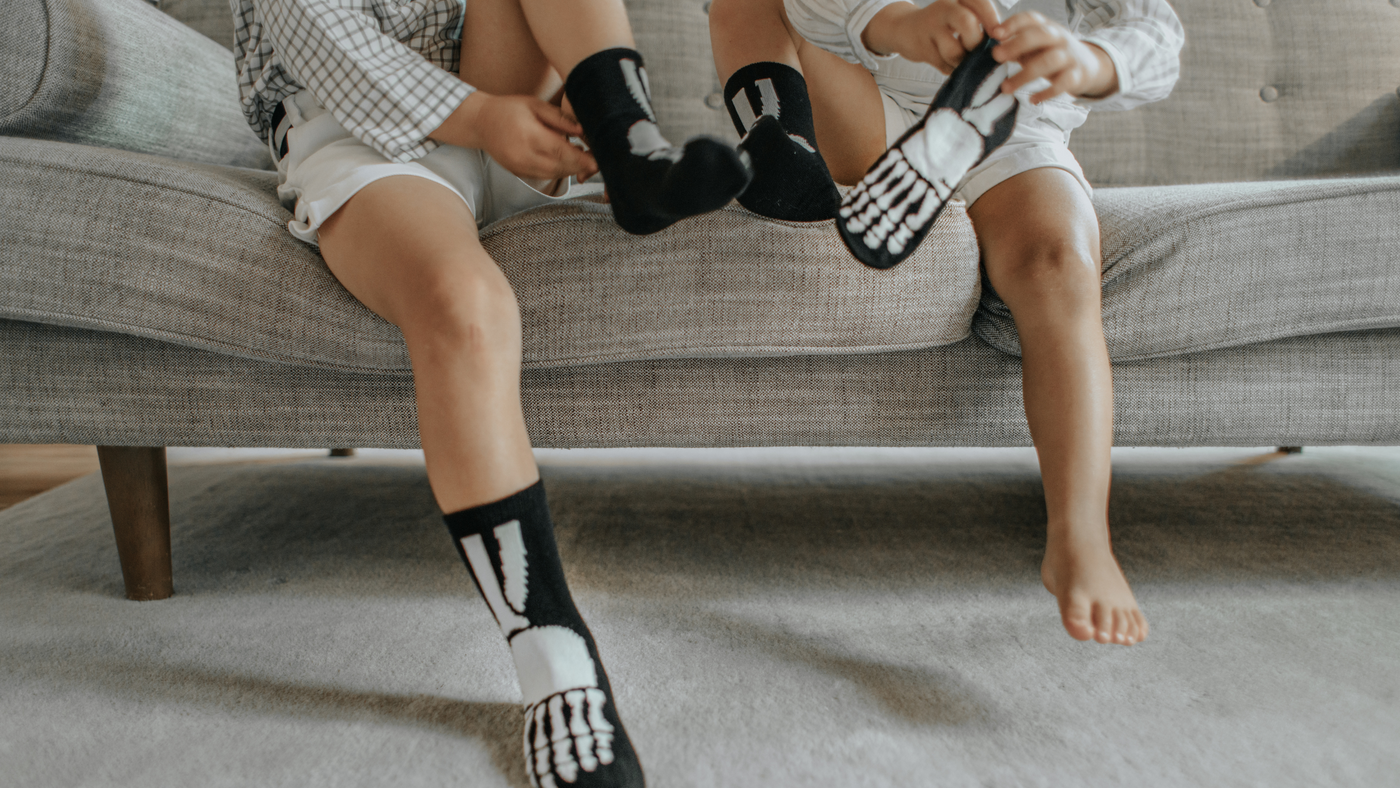 two little boys on the sofa putting on skeleton style socks