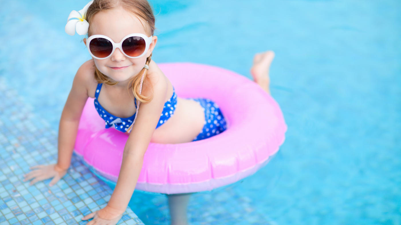 little girl in swimming pool wearing polka dot bikini and sunglasses
