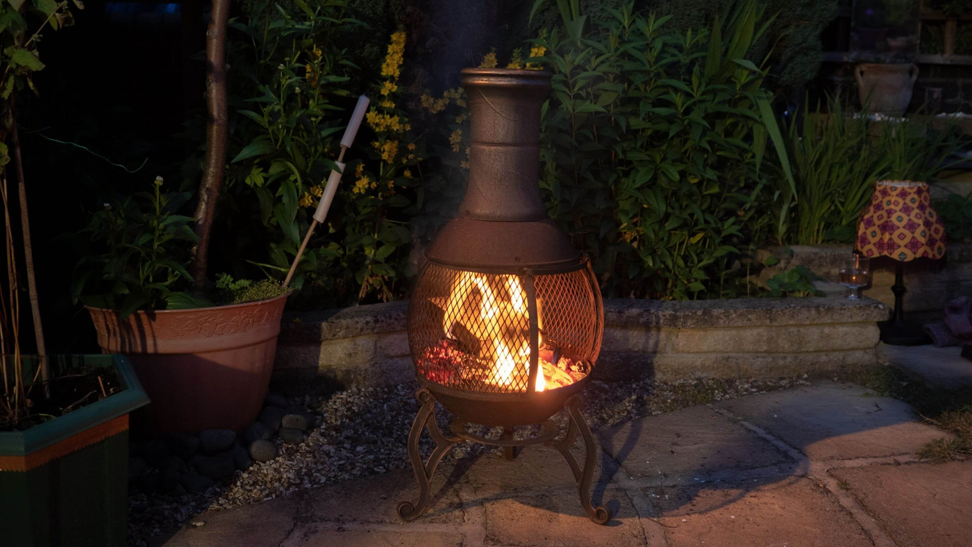 chiminea in garden at night, with flames inside the bowl