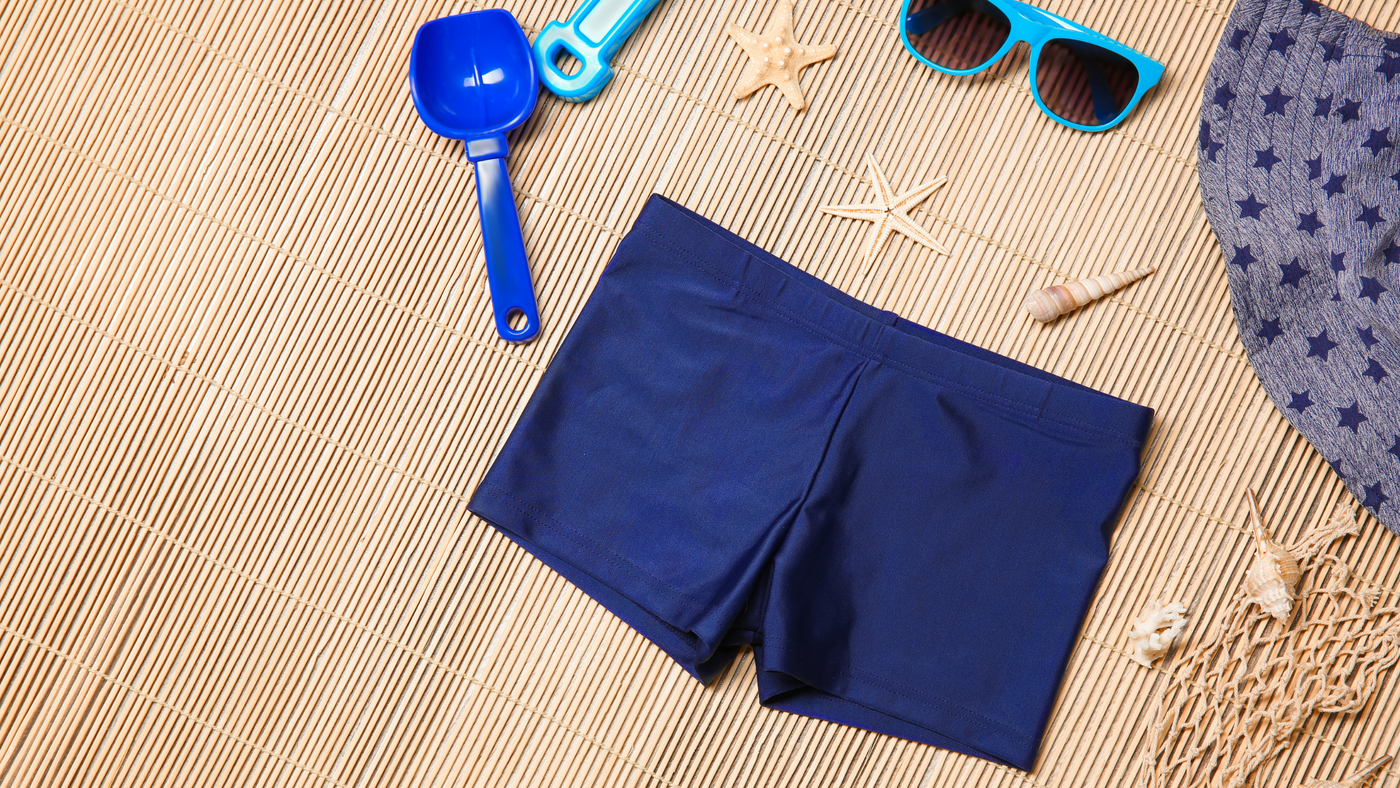 little boys beach accessories including sunglasses, swim shorts and beach toys