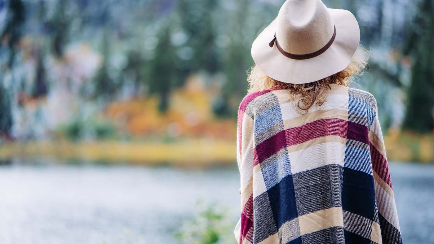 lady wearing striped poncho and summer hat in outdoor setting