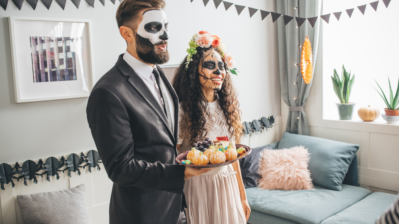 couple hosting guests dressed in matching day of the dead themed costumes