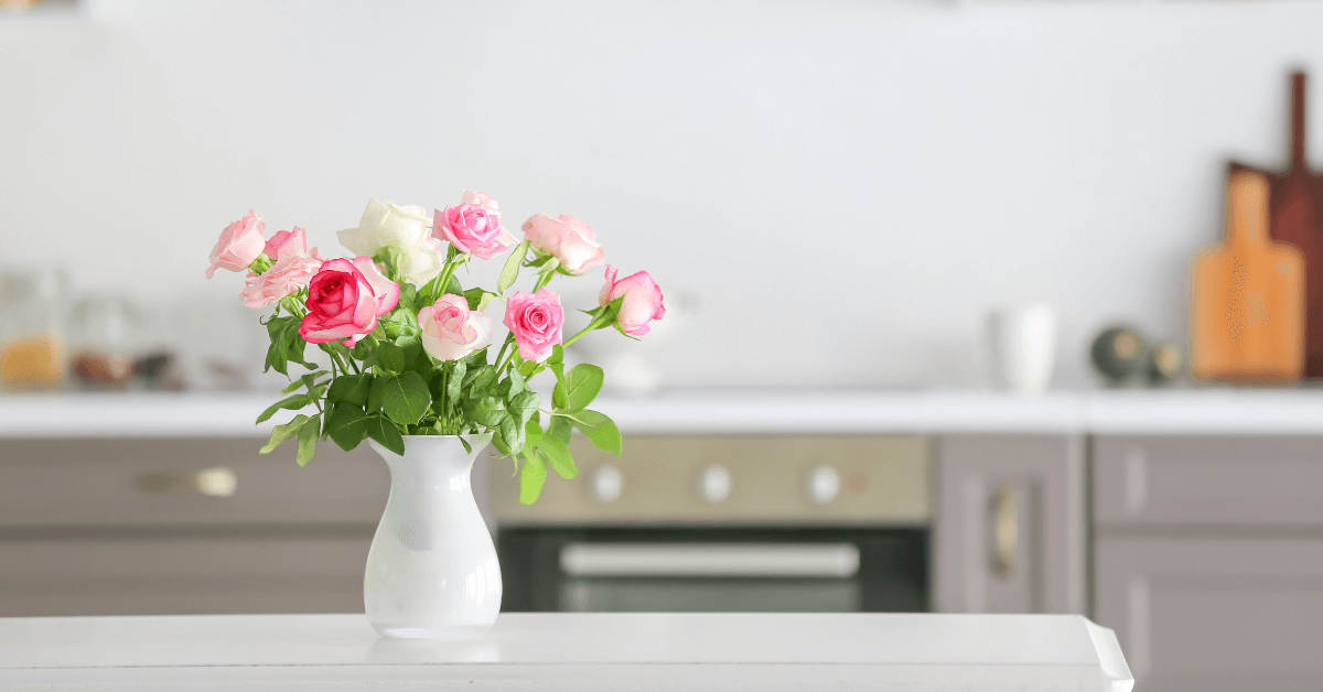 white glazed vase filled with pink and white roses resting on white kitchen counter