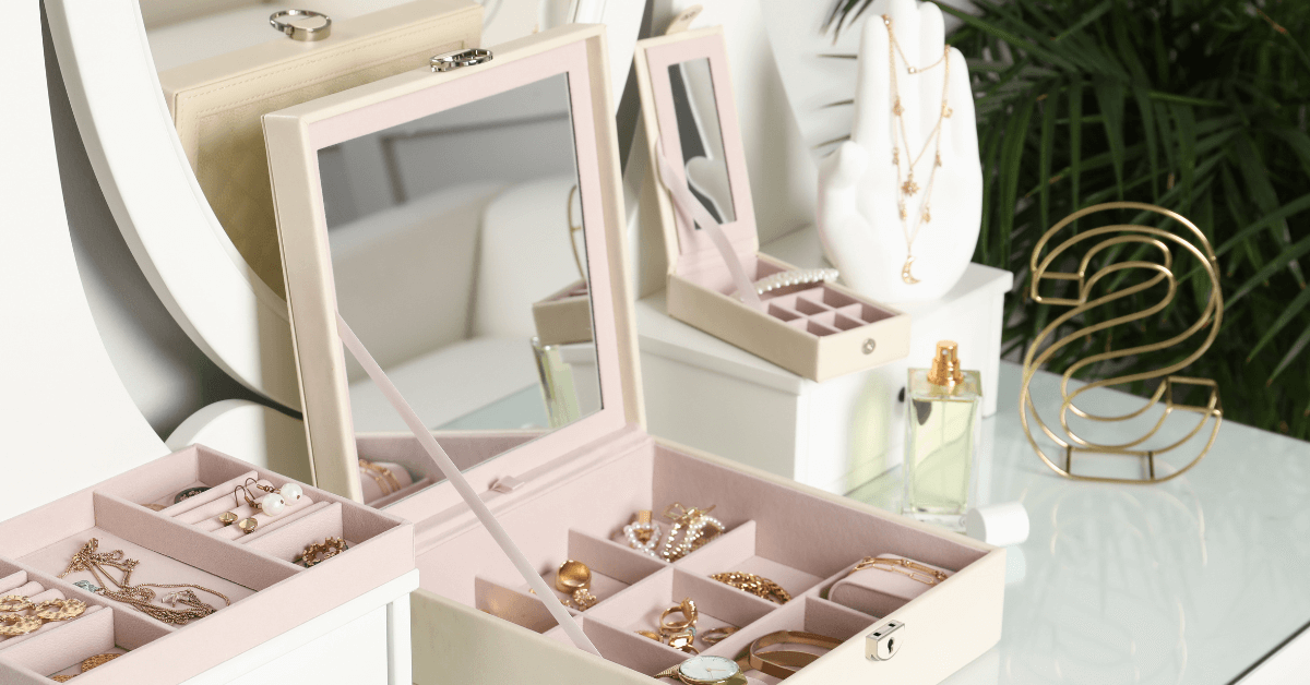 jewellery box filled with jewellery resting on white vanity table top beside jewellery palm ring holder
