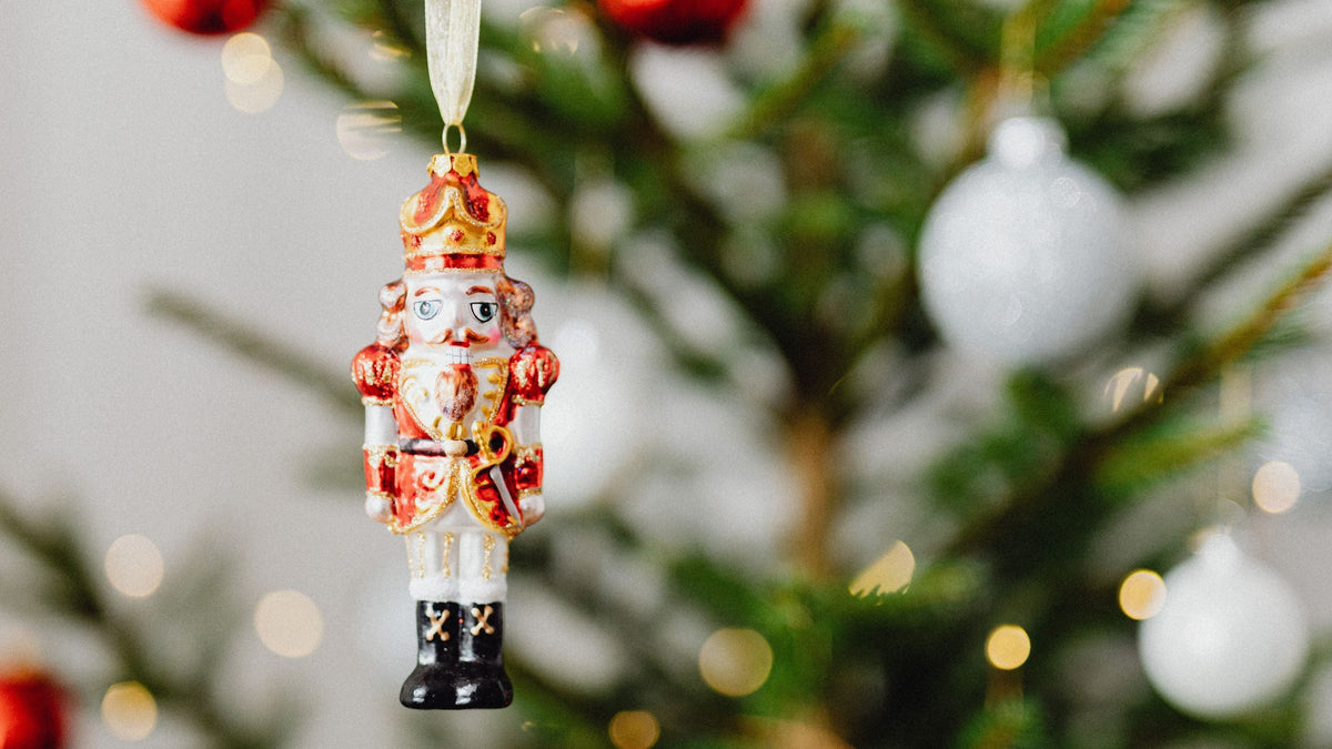 little nutcracker christmas tree decoration hanging in front of chritmas tree with warm white LED lights