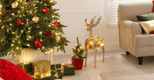 christmas tree with warm white lights beside christmas gifts and cream coloured sofa