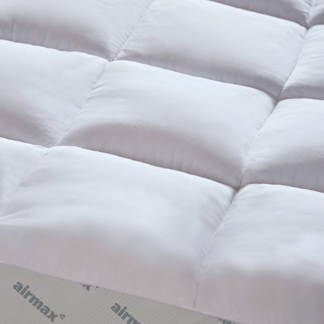 Close-up of a quilted mattress pad with 'airmax' branding.