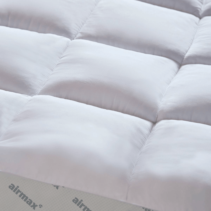 Close-up of a quilted mattress pad with 'airmax' branding.