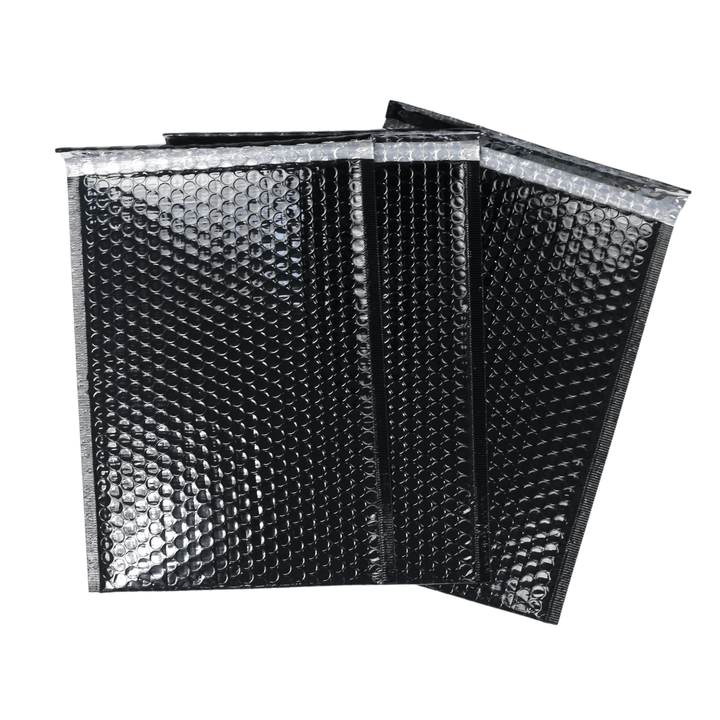 set of 3 black bubble mailers piled on top of each other on black background