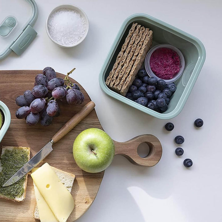 Looking down on a chopping board with Curver square food storage green container with blueberries and apple