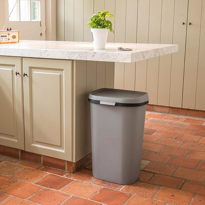 grey and black waste bin in a kitchen with tiled floor and basil plant