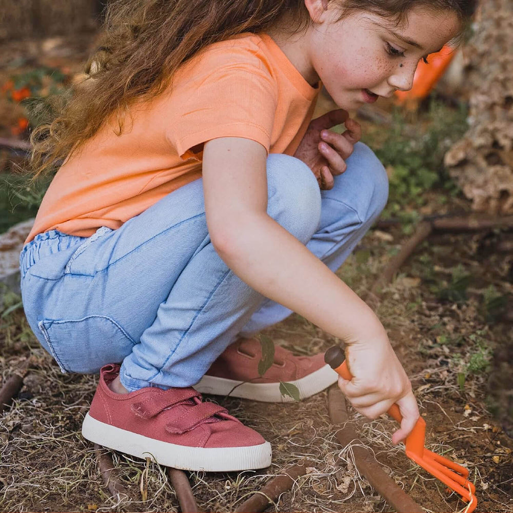 Girl using a kids garden hand fork tool to help in the outdoors