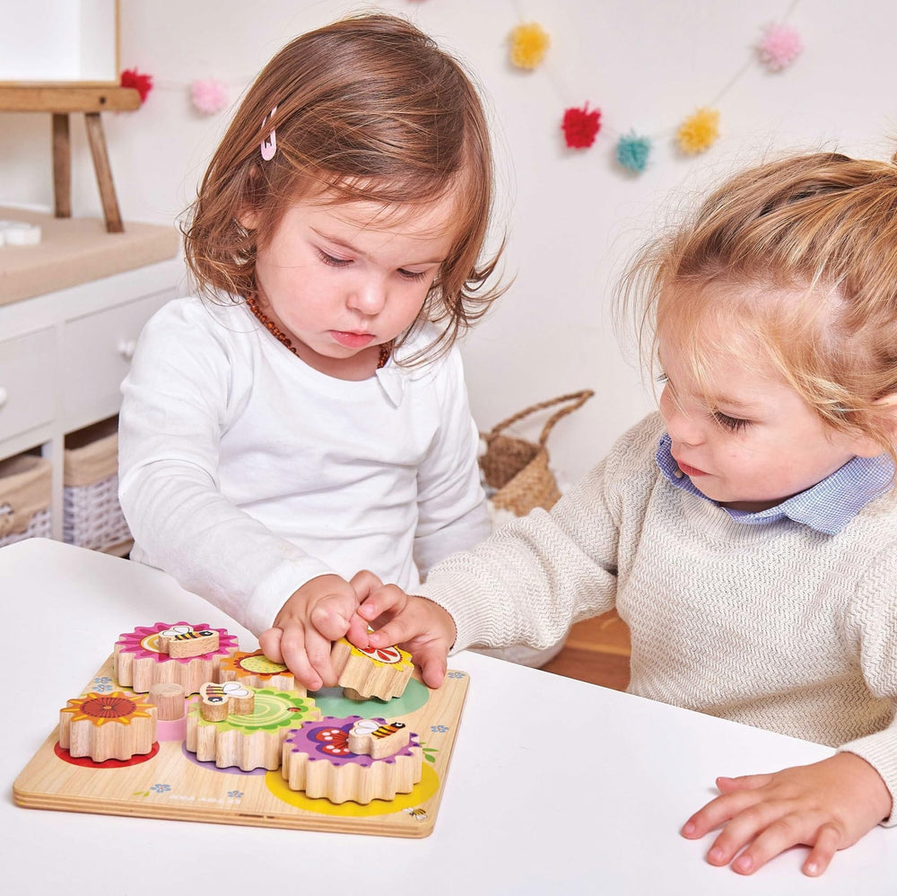 Two children playing with a wooden puzzle on a table.