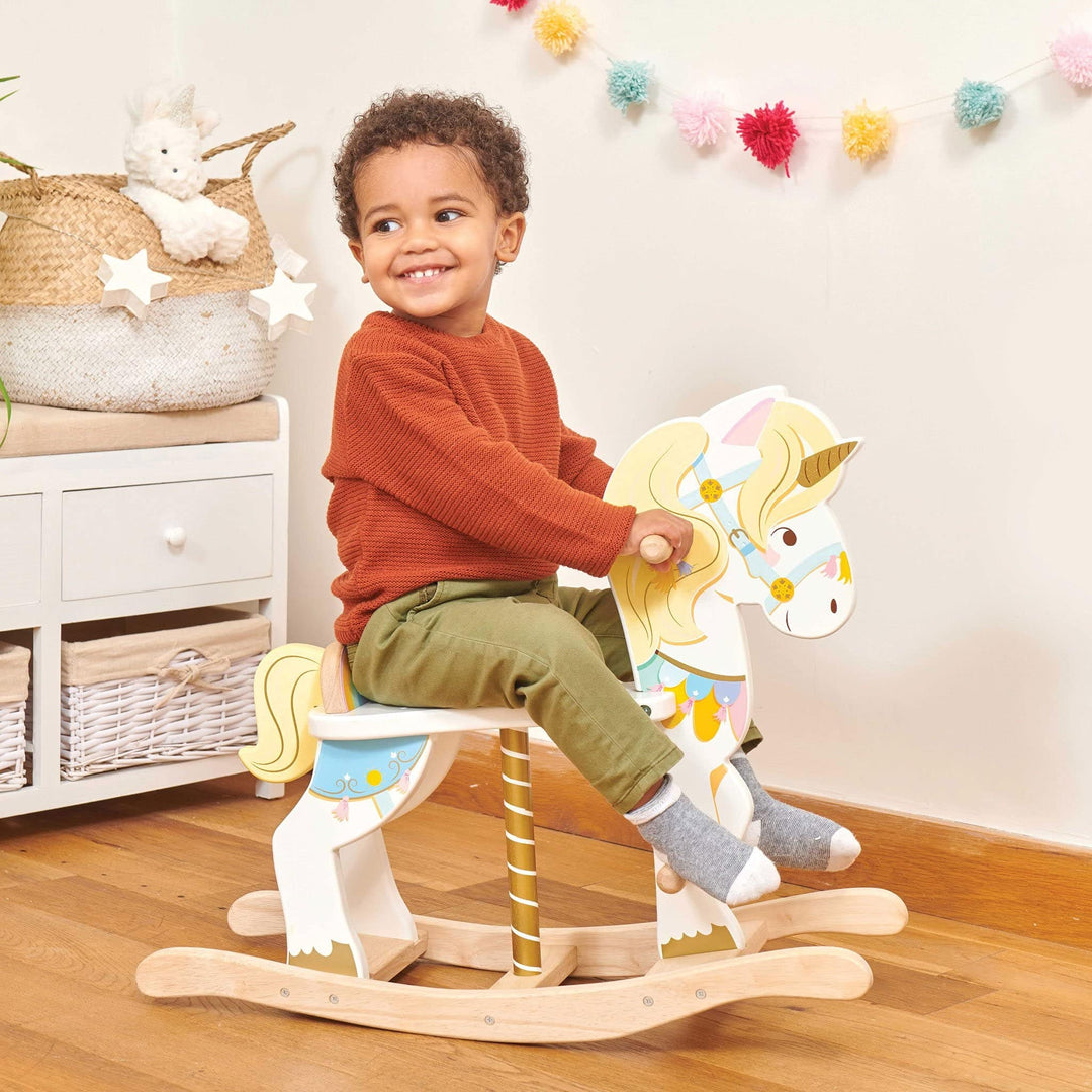 Child sitting on a wooden rocking horse in a room with decorative items.