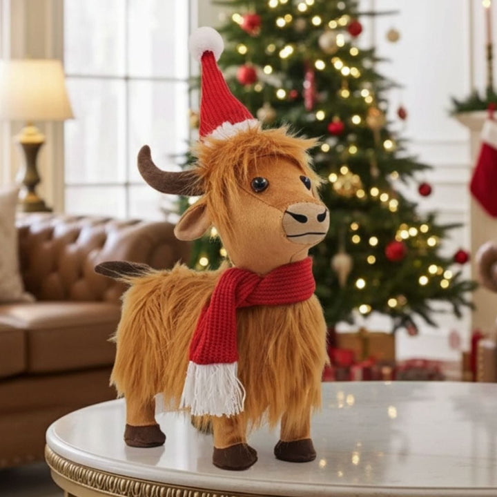 Plush highland cow wearing a Santa hat and scarf in front of a decorated Christmas tree.