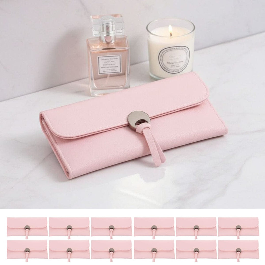 Pink clutch purse with a candle and perfume bottle on a white surface