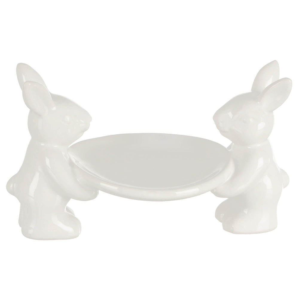 White ceramic cake plate with two rabbit figures on a white background
