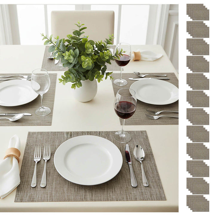 Dining table setting with white plates, silverware, red wine, and a vase of greenery.