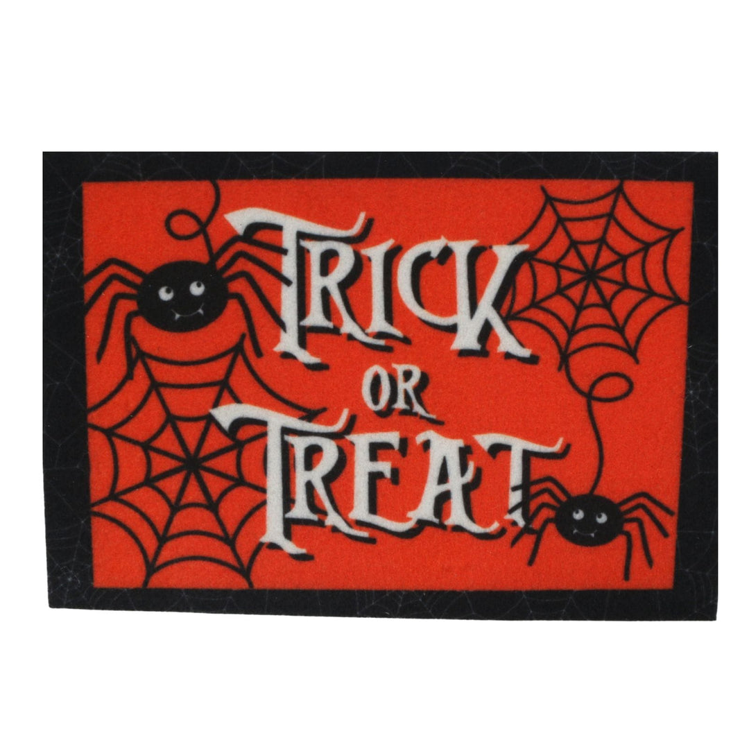 A rectangular Halloween doormat with a bright red background, black spiderwebs, two black cartoon spiders, and the words 'TRICK OR TREAT' in large white gothic lettering, finished with a black border.