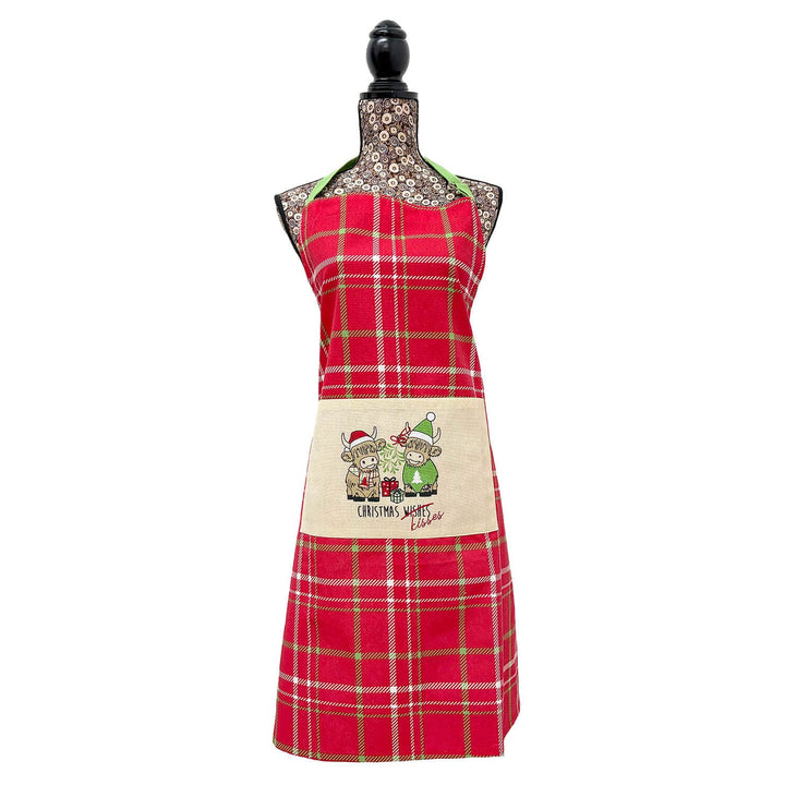 A red tartan Christmas apron with two Highland cows on the pocket displayed on a mannequin