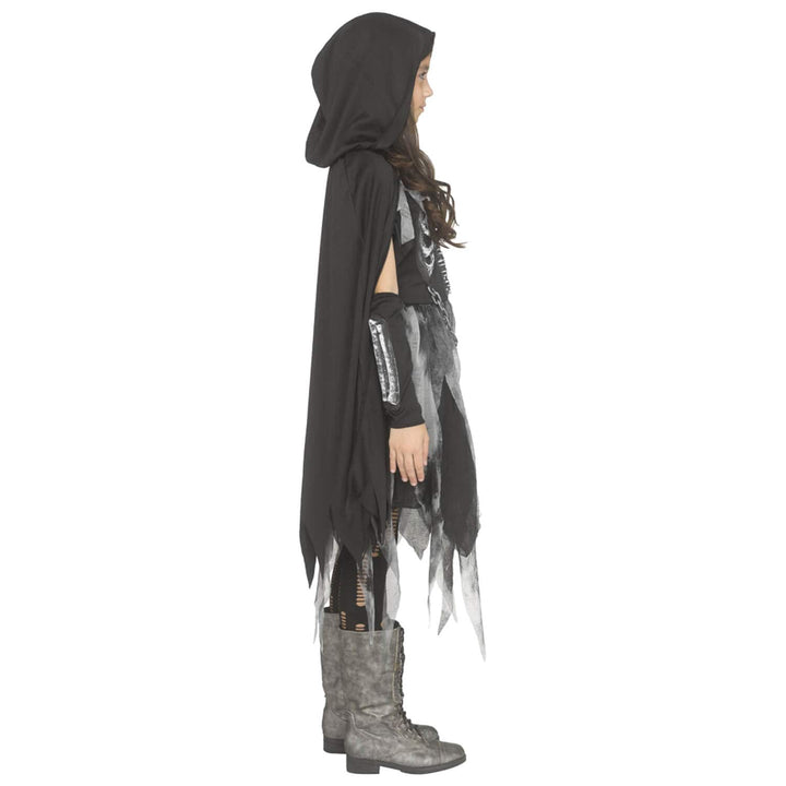 A child model shown in profile wearing a black hooded cape with tattered edges, a distressed black-and-white top, black arm warmers, and gray lace-up boots against a plain white background.