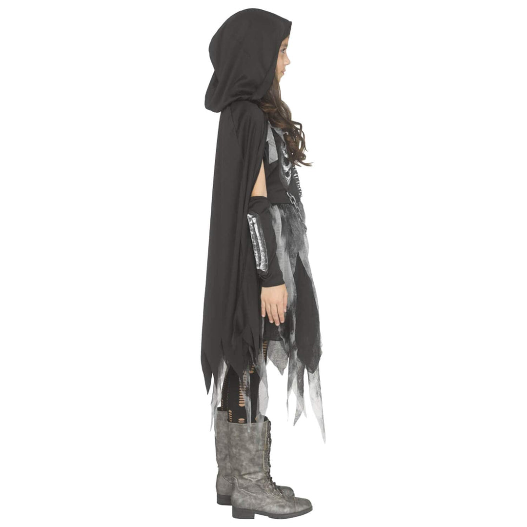 A child model shown in profile wearing a black hooded cape with tattered edges, a distressed black-and-white top, black arm warmers, and gray lace-up boots against a plain white background.